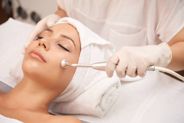 Cosmetologist using microdermabrasion machine for peeling, view from above