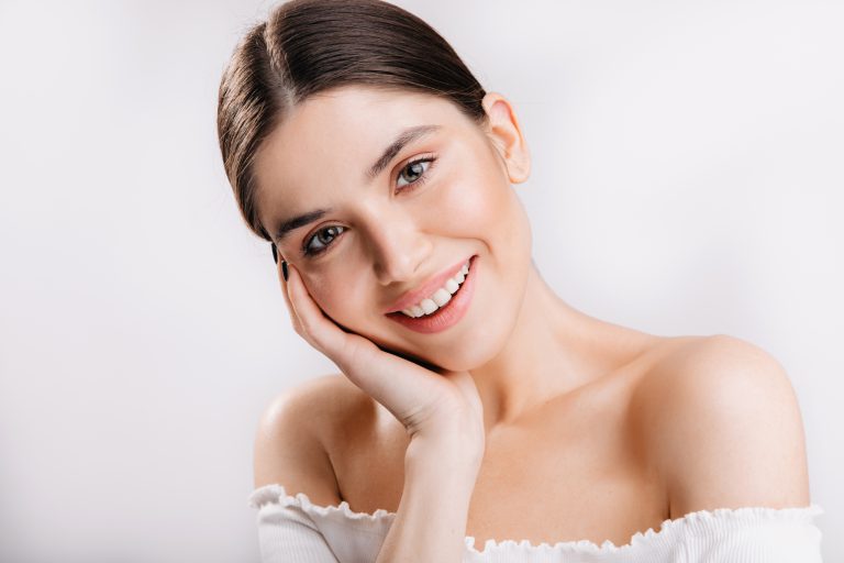 Portrait of smiling girl with healthy skin. Cute dark-haired woman looking at camera on white background