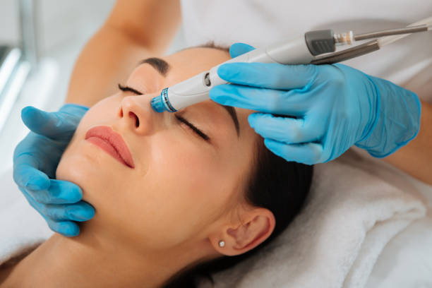 Facial procedure. Delighted nice woman lying on the medical bed with her eyes closed while having Hydradermabrasian