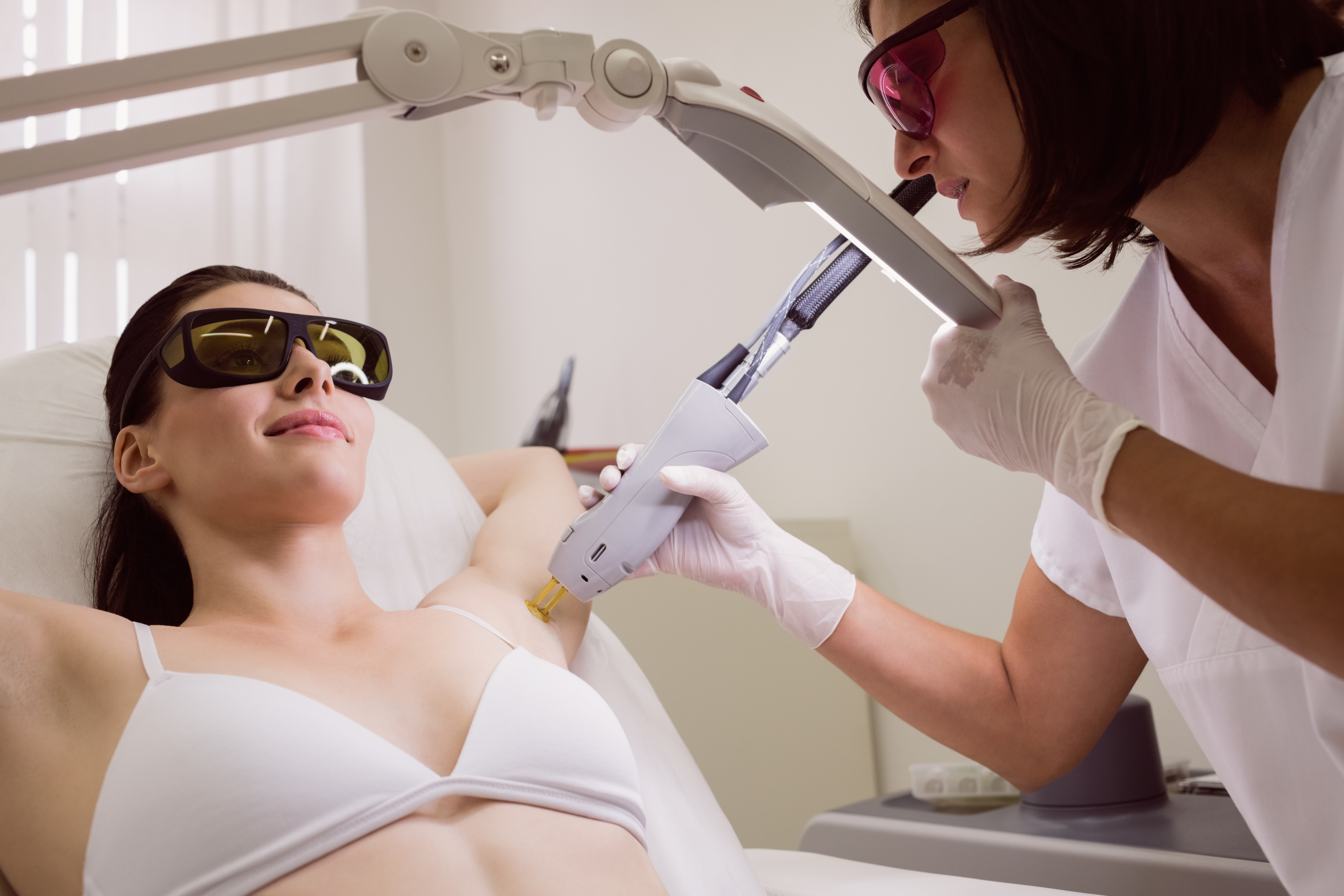Doctor performing laser hair removal on patient skin in clinic